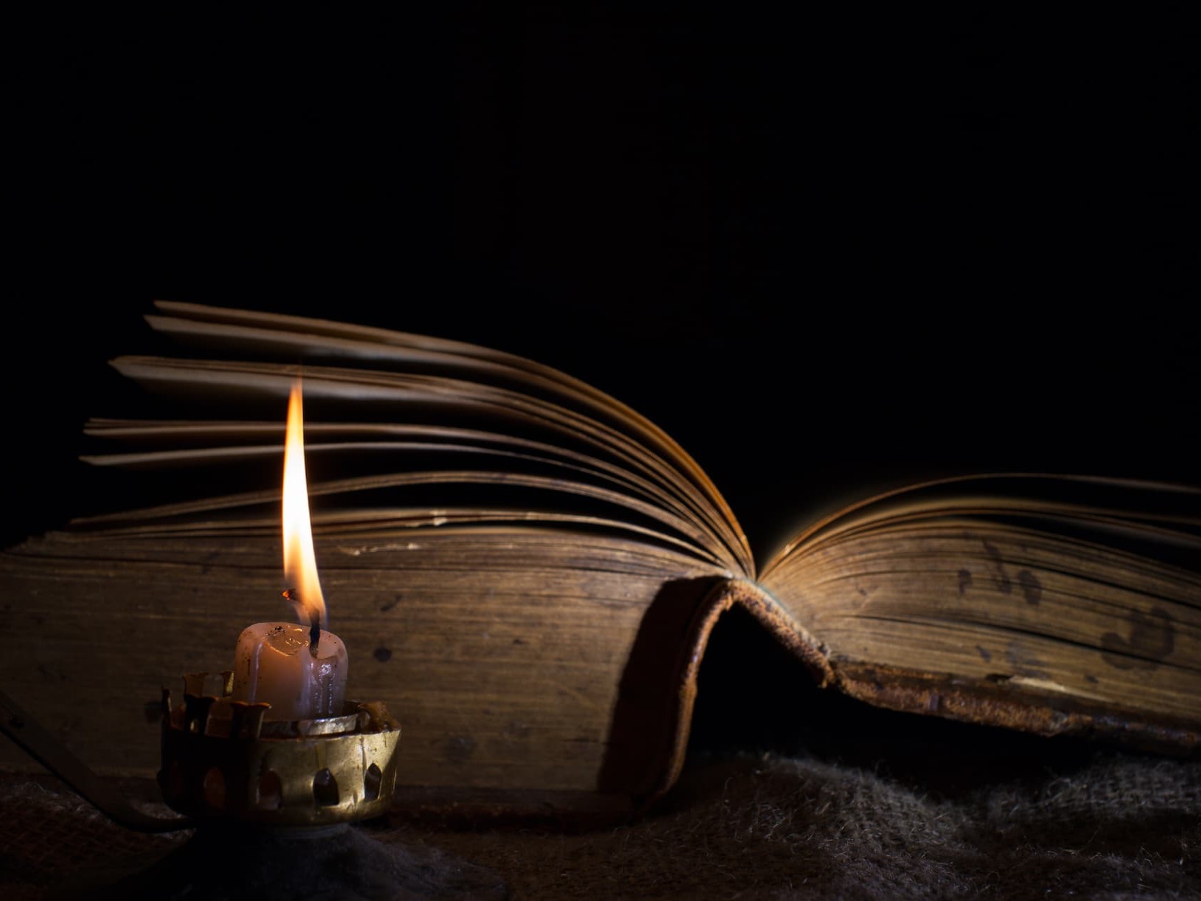 Antique books, a quill pen and ink bottle in candlelight